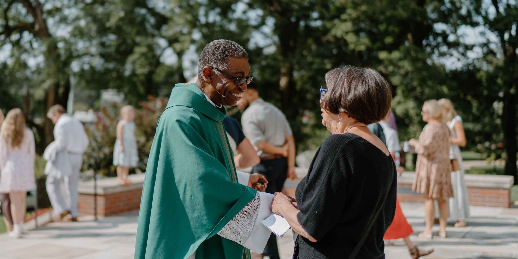 Fr. John Raphael of Christ the King Church greeting a female parishioner outside the church.